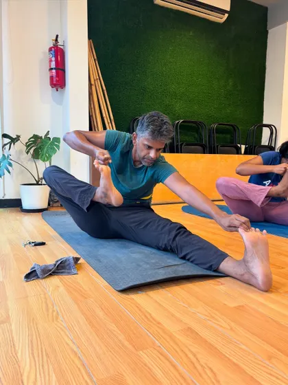 A student works on a deep seated forward split, a testament to his dedication and flexibility.