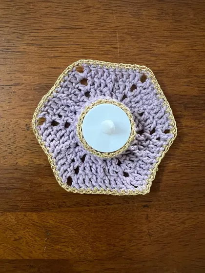 A single hexagonal tealight holder, unlit, on a wooden table. This simple, elegant piece is perfect for adding a touch of handmade warmth to any small space.