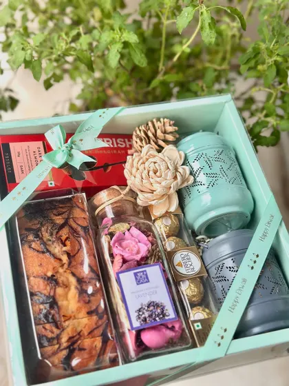 The "Scented Bliss" hamper is a treat for the senses. This Diwali box features two festive lanterns, chocolate-coated almonds, a potpourri jar, and a delicious marble tea cake.