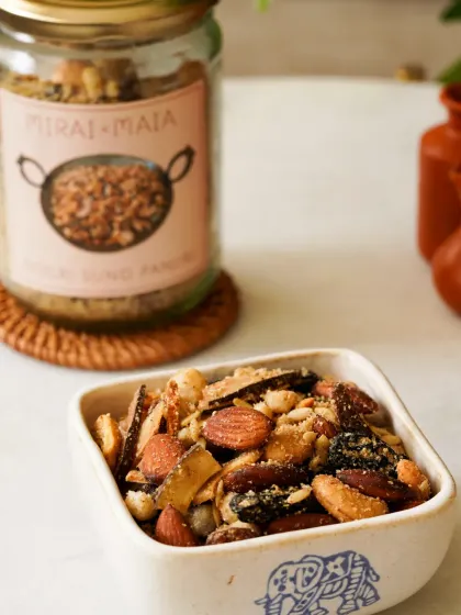 A close-up of a traditional panjiri mix, with the product jar in the background. The focus is on the texture and ingredients of the snack.