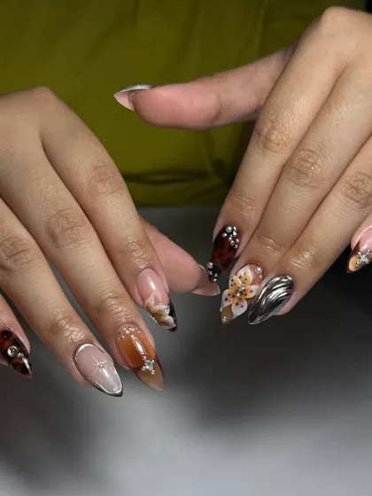 A complex and artistic set featuring a mix of textures and embellishments, including 3D chrome, floral painting, and rhinestones.