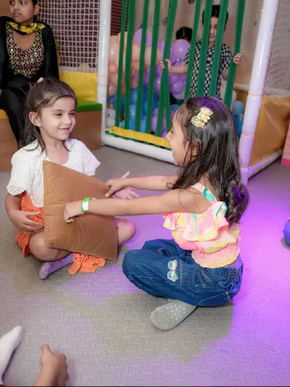 Two girls play a game of pass the pillow, laughing and having a great time.