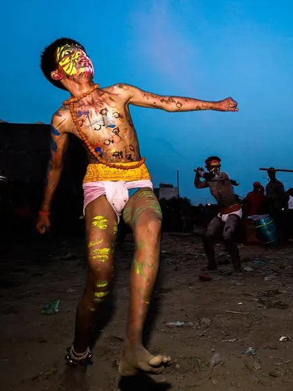 A young man dances with abandon during the Gajan festival, his body painted and his expression one of pure ecstasy.