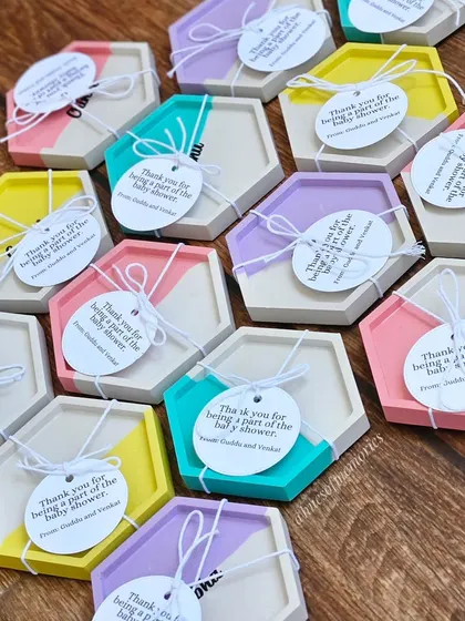 A full view of the custom name coasters made for a baby shower return gift. Each one is tied with a personalized 'Thank You' tag from the parents-to-be.