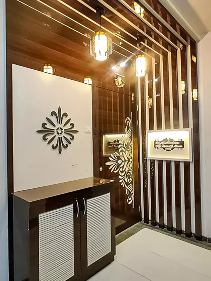 This foyer design has a luxurious feel, with glossy, dark wood paneling and decorative metalwork. The small cabinet provides essential storage without cluttering the grand entrance.