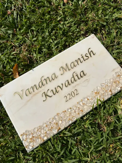 Another view of the white marble nameplate with a natural stone border. The combination of the smooth resin and the textured stones creates a wonderful tactile and visual contrast.