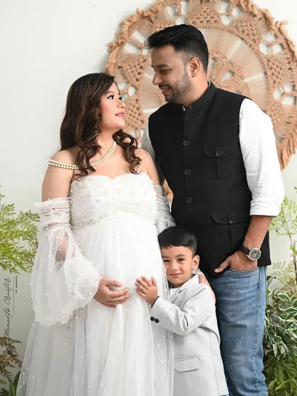A beautiful family moment. The older son peeks out from behind his parents, adding a touch of playfulness to this lovely family portrait.