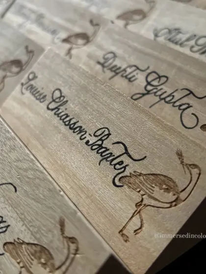 This image highlights the contrast between the dark, delicate calligraphy and the light wood. These name plates are not just for finding a seat, they are a personalized party favor for guests to take home.