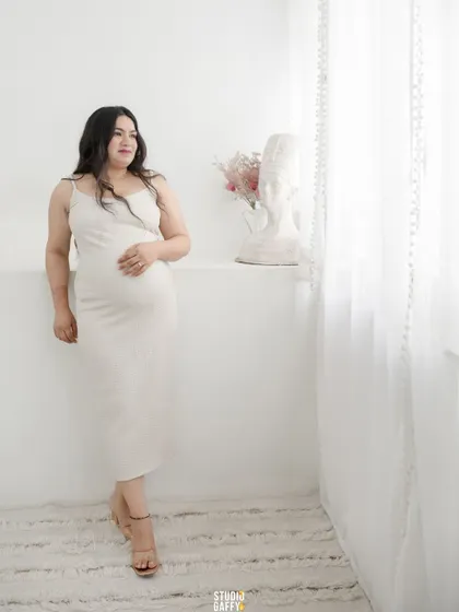 A full-length portrait of the mother-to-be by the window, using natural light to create a soft and ethereal glow.
