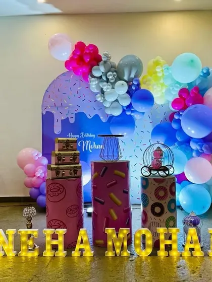 The full setup for the sweet treats theme, including donut-printed pedestals and large marquee letters for the name 'Neha Mohan'.
