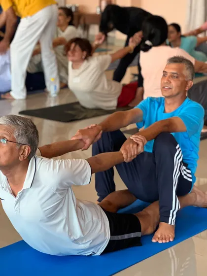Two men practice an assisted bow pose. Partner work is a great way to safely deepen backbends and build trust.