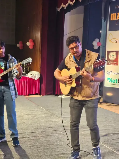 A teacher and student duo performing a guitar piece at the Madfit 2023 concert.