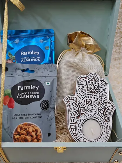 A healthy and elegant corporate gift option. This trunk box is filled with premium Farmley cashews and almonds, a potli of treats, and a beautiful Hamsa-hand tealight holder for a touch of wellness.