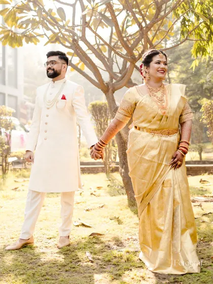 A beautiful portrait of a South Indian couple, holding hands and smiling, captured in the soft light of an outdoor setting.