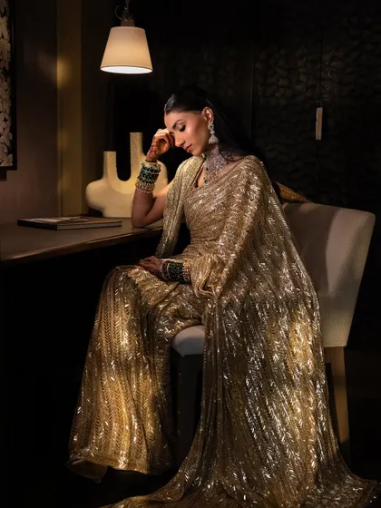 A full-length artistic shot showing the magnificent drape of the golden saree. The makeup remains flawless and elegant.