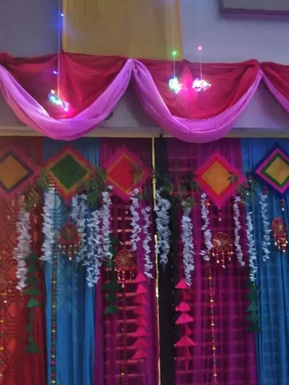 A house gate decorated with colorful drapes and hanging props, creating a welcoming entrance for guests.