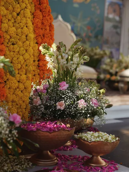 A detail shot of the fresh flowers, including tuberose and baby's breath, arranged in brass bowls alongside marigold structures.