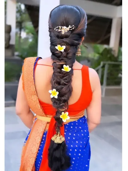 A modern messy braid decorated with fresh yellow flowers and a contemporary hair clip at the top.