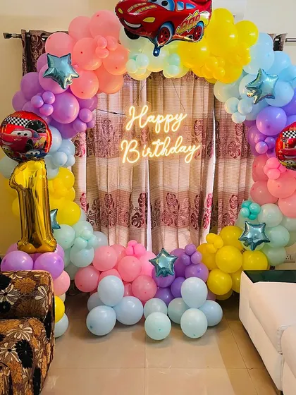 A centered view of the "Cars" balloon ring, with the "Happy Birthday" neon sign glowing in the middle.