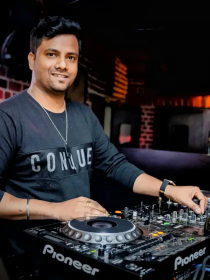 A smiling shot from behind the Pioneer decks at a club night. I am comfortable and experienced with all professional-grade DJ equipment.