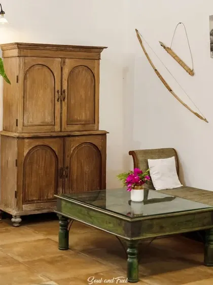 A cozy corner in Z Farms, with rustic wooden furniture and a traditional bow and arrow as wall decor. The space has a warm, earthy, and lived-in feel.