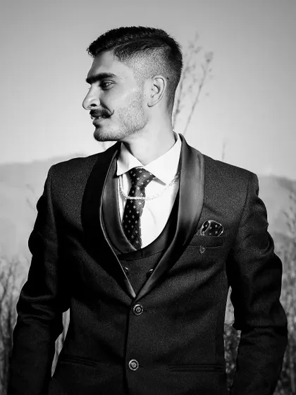 A classic black and white groom's portrait. This timeless look emphasizes his sharp suit and confident expression against a natural, textured background.