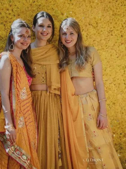 Guests enjoying the Haldi ceremony. The wall of yellow flowers provides a perfect, on-theme backdrop for photos and adds to the festive spirit of the event.