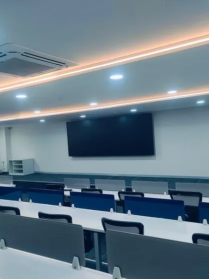 The main auction hall at the TVS Centre, designed for clarity and focus. The tiered seating ensures clear sightlines to the main screen, and the clean, modern aesthetic provides a professional backdrop for high-value transactions.
