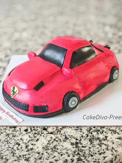 A carved Ferrari cake for a car enthusiast. I shaped this cake by hand and covered it in red fondant, paying close attention to the car's sleek lines and details.