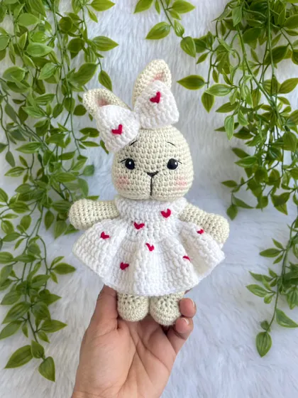 This sweet bunny is dressed in a white frock adorned with little red hearts. The matching bow on her ear makes her extra cute. A perfect gift for Valentine's Day or for someone you love.