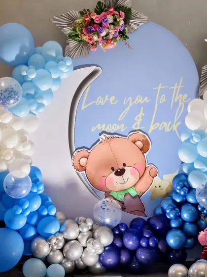 A detail shot from Kian's teddy bear party, showing the 'Love you to the moon & back' sign and the beautiful blue balloon arrangements.
