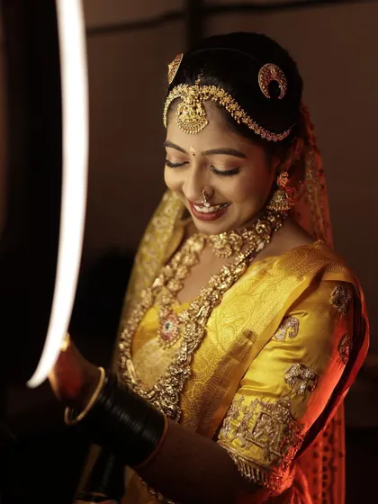 A creative shot of the bride, with the warm light highlighting the detailed embroidery on her blouse sleeve.