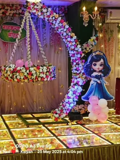 A princess-themed naming ceremony stage with a floral moon-shaped cradle. The combination of cartoon princess cutouts and elegant floral work makes it a perfect choice for welcoming a baby girl.