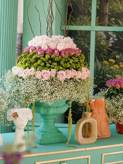A tiered floral arrangement in a mint-green urn, a signature piece of the 'Mint to Be' decor. The layers of pink roses and baby's breath are simply stunning.