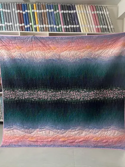 A beautiful quilt featuring a printed scenery of cherry blossom trees, enhanced with custom longarm quilting.