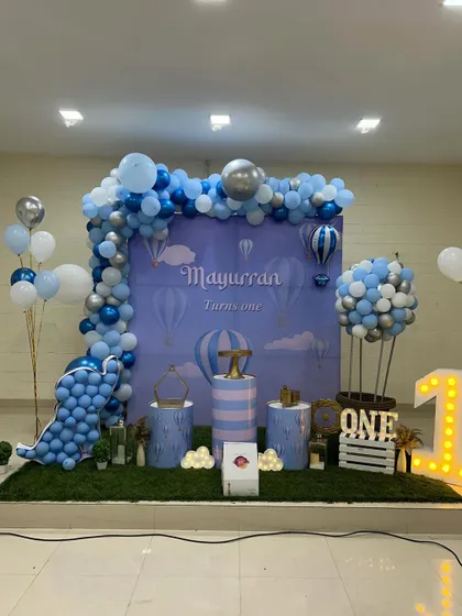 A gentle and dreamy Hot Air Balloon theme for a first birthday. The setup uses a soft blue color palette with a custom backdrop and a balloon sculpture shaped like a hot air balloon.