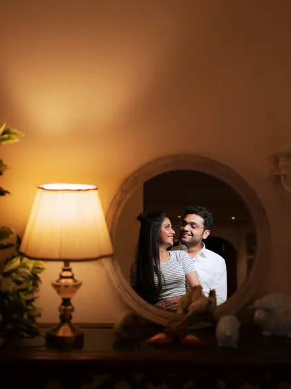 An artistic and intimate portrait using a mirror and warm lamplight. This creative technique adds a layer of depth and romance to an indoor pre-wedding shoot, creating a moody and memorable image.