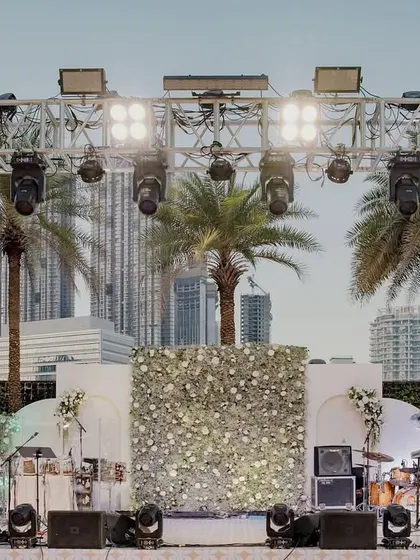 The stage for the 'White Wonderland' event, with the city skyline of Dubai creating a stunning modern backdrop. The stage itself was adorned with a wall of fresh white flowers.