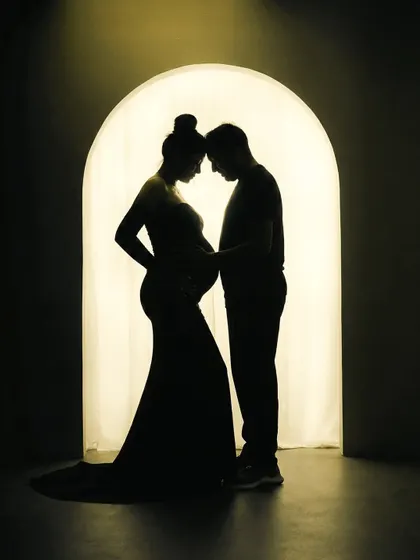 There is a special magic in silhouette portraits. This image focuses purely on the connection between the expecting parents, their shapes telling a story of love and anticipation against a warm, glowing archway in my studio.