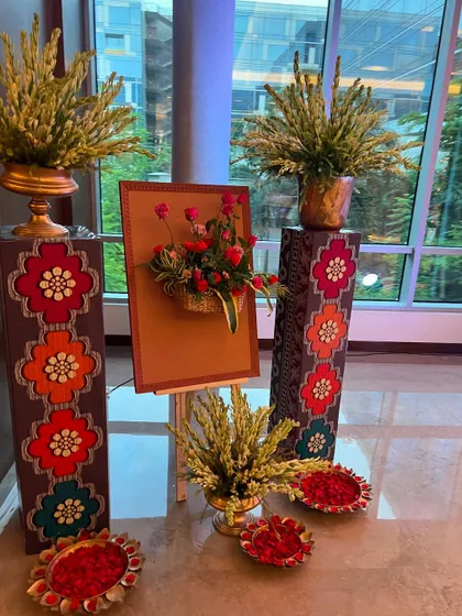 Detail of the decor for a luxury Mehendi setup, showing floral arrangements on decorative pedestals and bowls of rose petals for guests.