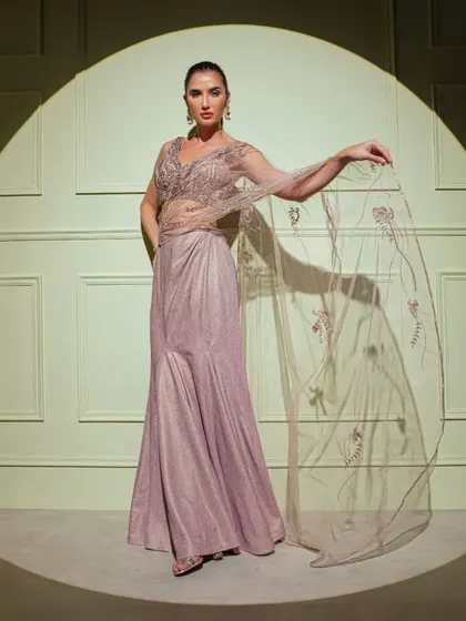 Captured in the spotlight, this mauve fish-cut gown features a sheer embroidered cape, adding a layer of ethereal beauty to the structured silhouette.