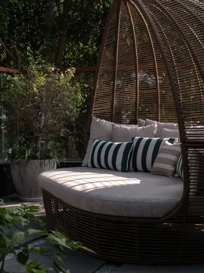 A cozy daybed on the terrace, surrounded by greenery. This is the ultimate spot for a cup of chai and a good book, feeling completely immersed in nature.