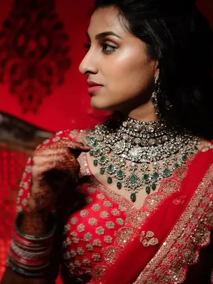 A stunning portrait of a bride in her red reception lehenga, bathed in dramatic red light. This bold and colorful shot showcases her regal look.