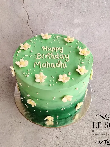 The shades of green on this cake were chosen to match the party decor. This 1.5 kg tall Vanilla Butterscotch cake features a green ombre effect and is dotted with tiny white flowers.