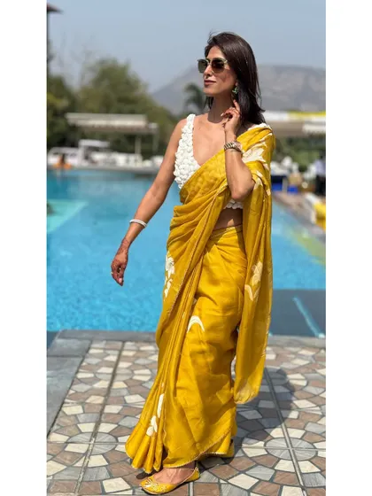 A full-length shot of me walking in the hand-painted saree, showcasing its graceful movement. Paired with matching yellow juttis, the look is cohesive and effortlessly elegant.