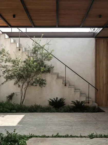 A tranquil internal courtyard creates a pocket of calm and nature within the home. The design uses a simple palette of concrete, wood, and glass to create a minimalist and serene atmosphere.