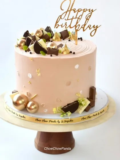 An elegant chocolate-themed cake. This Chocolate Truffle cake is decorated with pieces of chocolate, Oreos, and gold spheres for a rich and decadent look.