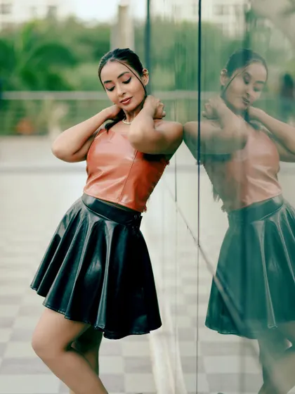 A fashion portrait using reflections to create depth. The model's pose against the glass wall adds a layer of sophistication and modernity to the shot.