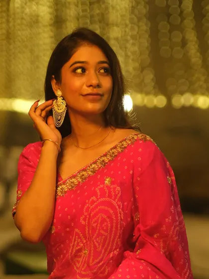 Adjusting her earring against a backdrop of golden bokeh lights, this portrait captures a classic, elegant moment during the Dev Deepawali festival.