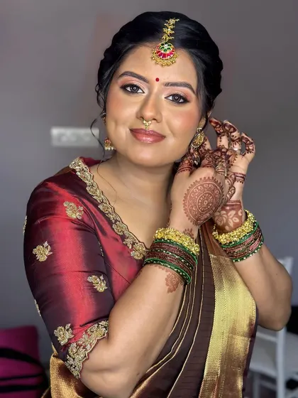 A portrait of a gorgeous bride in a deep maroon saree. The makeup is soft and subtle, with a focus on a flawless base and gently defined eyes to complement her traditional attire.